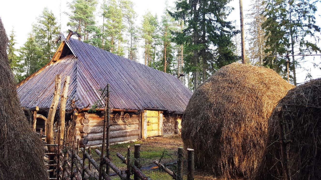 Vana palkhoone ees paistab puidust aed ja kaks suurt heinakuhja