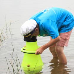 Sisise särgi ja meremehemütsiga noormees seisab järves ja uurib vee-elustikku