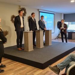 Kolm ülikondades meest seisavad reas ja vastavad noore kliimateadliku blondi tütarlapse küsimustele